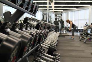 woman standing surrounded by exercise equipment by Danielle Cerullo courtesy of Unsplash.